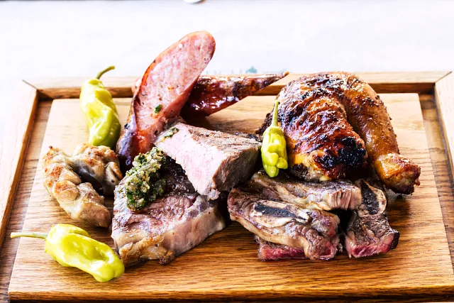 Grilled meats and peppers on a wooden board