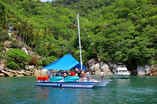 A trimaran anchored off a jungle-backed beach