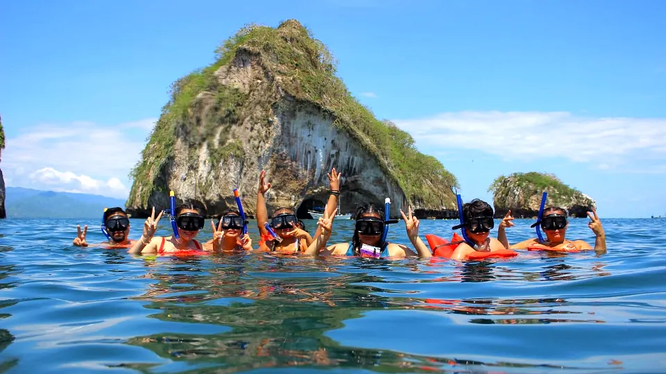 Snorkelers in clear water beside the Los Arcos rock formations