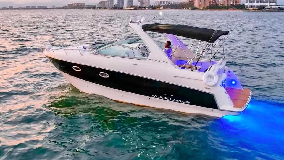A yacht at dusk with the Puerto Vallarta skyline glowing behind it